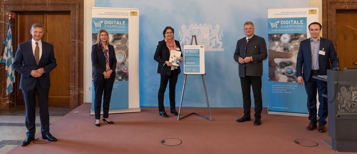 Die Spielkiste mit Sitz in Lam ist „Digitaler Champion im bayerischen Einzelhandel 2021“ (v.l.): Wolfgang Puff (Hauptgeschäftsführer Handelsverband Bayern e.V.), Simone Wastl (Leitung Unternehmenskommunikation und Marke, Mitglied der Geschäftsführung DATEV eG), Emmi Kollross (Geschäftsführerin Spielkiste), Wirtschaftsstaatssekretär Roland Weigert und Dr. Johannes Faltermeier (Projektleiter ibi research an der Universität Regensburg GmbH). Foto: Elke Neureuther/StMWi