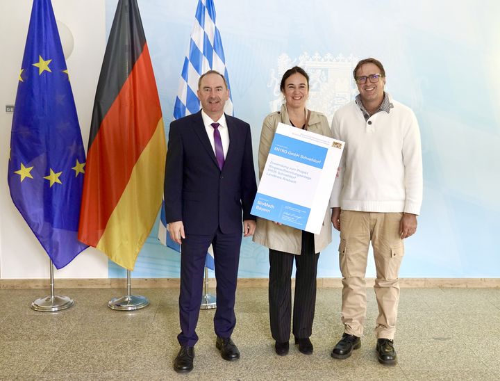 Bayerns Wirtschafts- und Energieminister Hubert Aiwanger hat heute die erste Förderurkunde aus dem Förderprogramm BioMeth Bayern des Wirtschaftsministeriums übergeben. Die Firma Entro GmbH aus Schnelldorf bei Wörnitz im Landkreis Ansbach erhält als erstes Unternehmen einen Zuwendungsbescheid für 40 Prozent der Investitionssumme aus dem Förderprogramm. Das Bild zeigt (von rechts nach links): Entro-Geschäftsführer Andreas Bühler, seine Frau Judith Adler und Wirtschaftsminister Hubert Aiwanger. Foto: StMWi/Aaron Gottardi