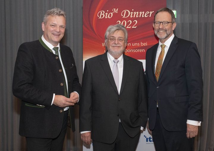 Beim traditionellen BioM Jahresabschluss-Dinner würdigte Bayerns Wirtschaftsstaatssekretär Roland Weigert (links) die Leistung von Prof. Horst Domdey (Mitte), der nach 25 Jahren die Geschäftsführung der Biotech Cluster Management-Organisation BioM zum 1. Januar 2023 an Prof. Ralf Huss (rechts) übergibt. Foto: BioM/Michael Woelke