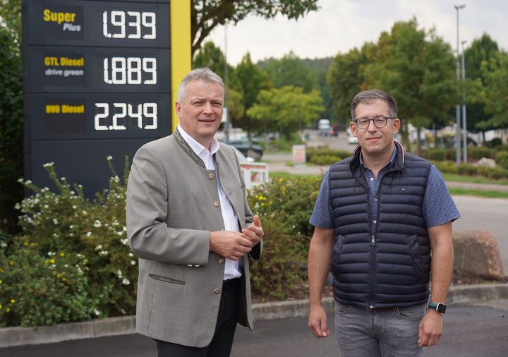 Wirtschaftsstaatssekretär Roland Weigert (l.) hat den Tankstellenbetreiber Nico Zieglmeier besucht, den gesetzliche Regelungen des Bundes daran hindern, den klimafreundlichen synthetischen Diesel HVO100 an Zapfsäulen in den Verkehr zu bringen. Foto: StMWi