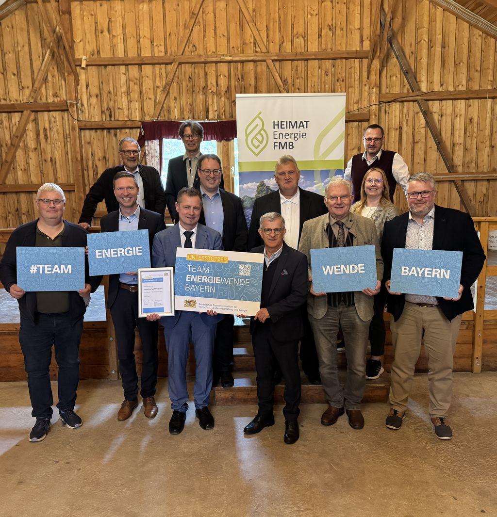 Ein Gruppenbild mit Personen, die Schilder des Teams Energiewende Bayern in die Kamera halten. Darunter Regierungspräsident Florian Luderschmid und Vertreterinnen und Vertreter der Heimatenergie FMB GmbH.